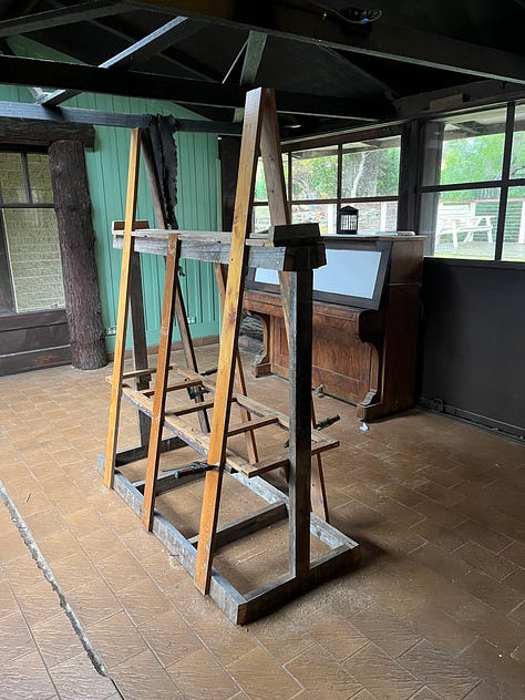 A wooden frame for storing and painitng wooden panels and tools and a series of coffee can lanterns in the process of being restored.