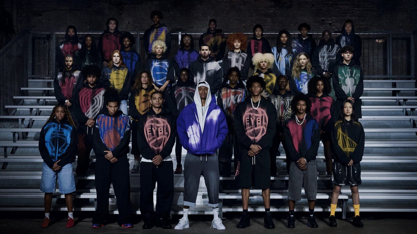 Large group of models in oversized basketball hoodies and jerseys posed on bleachers Large group of models in oversized basketball hoodies and jerseys posed on bleachers