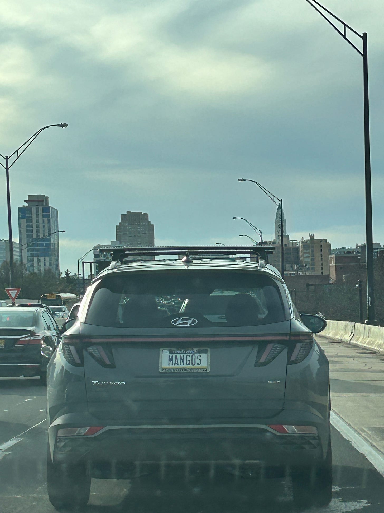An image of a car's license plate that reads "MANGOS." The car is on the highway.
