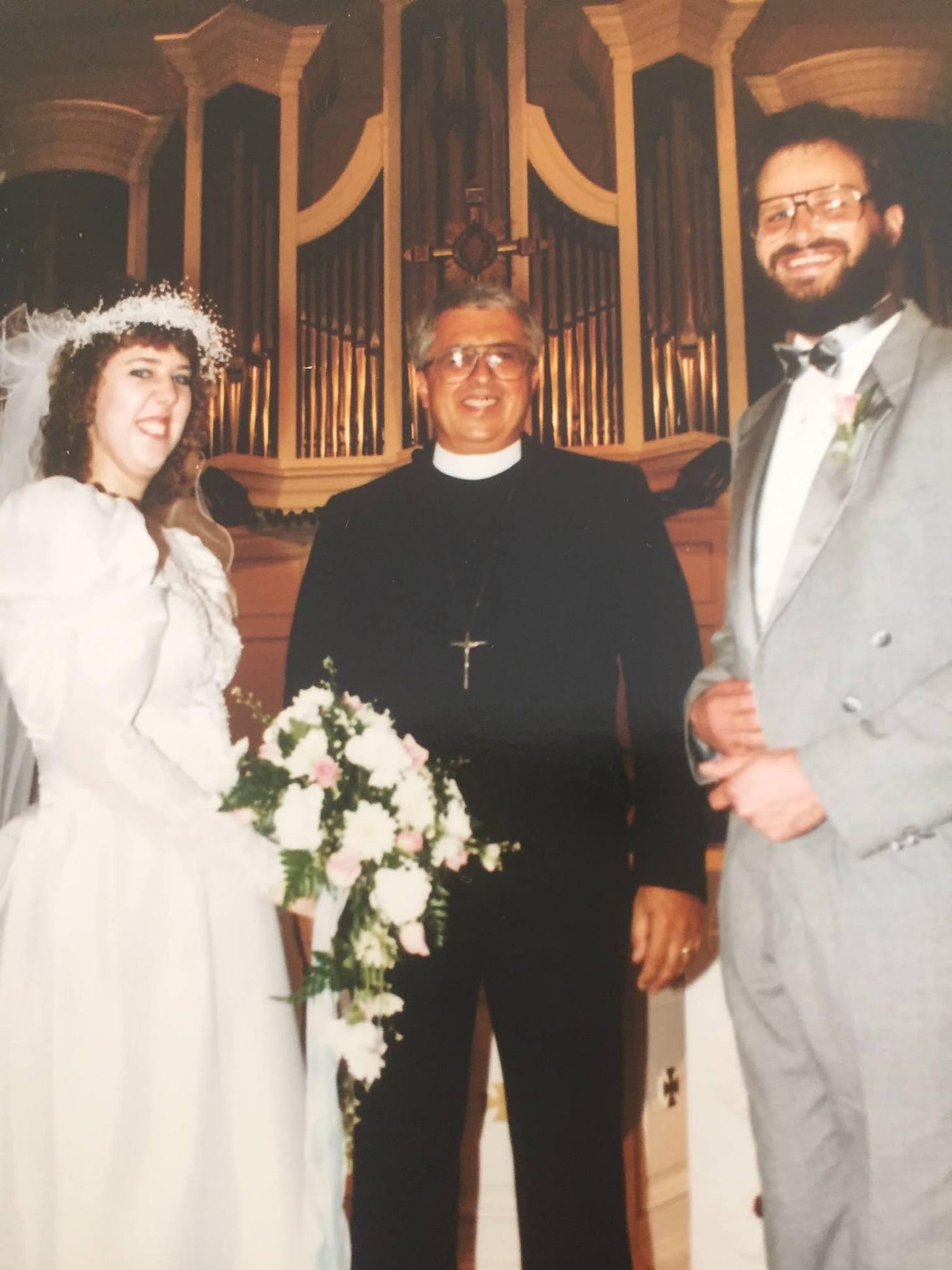 wedding photo of author and her husband with the pastor who married them