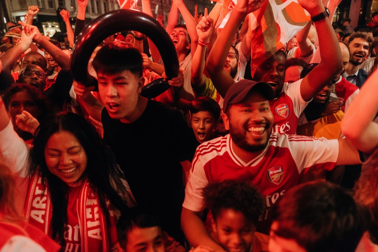 Frozen moment in time: extreme close-up view inside a crowd of Arsenal football fans, a variety of ages, races, and genders, dancing in a London street at night illuminated by red flares, jumping and shouting in joy and happiness, pure chaos. Frozen moment in time: extreme close-up view inside a crowd of Arsenal football fans, a variety of ages, races, and genders, dancing in a London street at night illuminated by red flares, jumping and shouting in joy and happiness, pure chaos.