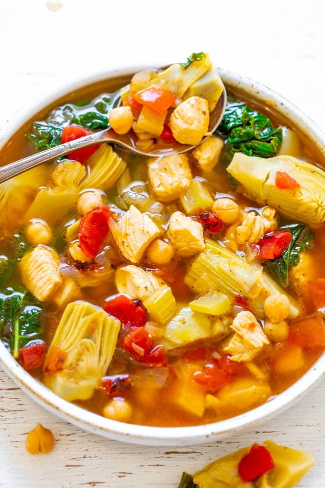 a bowl of chicken Mediterranean soup with a spoon resting on the side a bowl of chicken Mediterranean soup with a spoon resting on the side