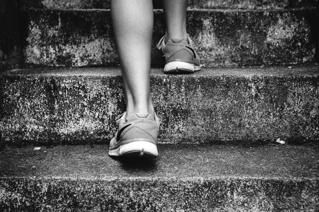 person wearing orange and gray Nike shoes walking on gray concrete stairs person wearing orange and gray Nike shoes walking on gray concrete stairs