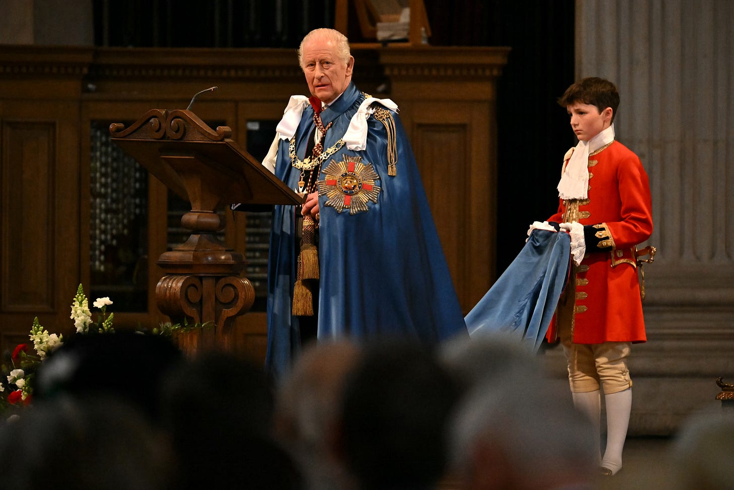 King Charles wearing a blue cloak with a boy holding the end of the cloak behind him