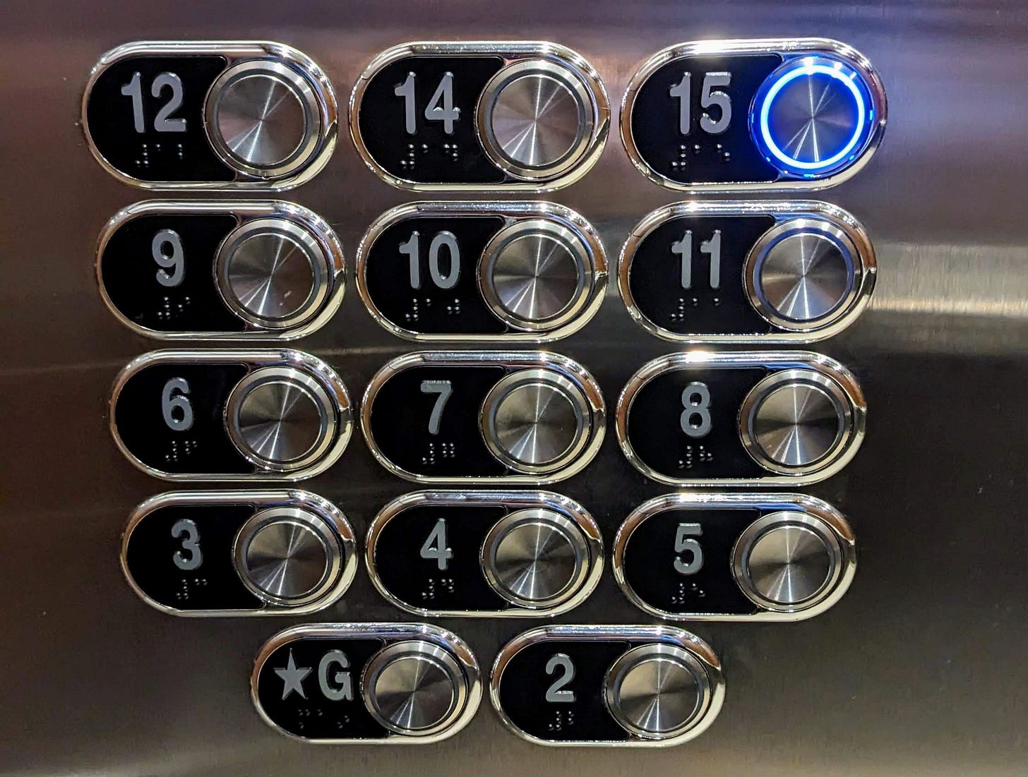 Elevator panel with the 15th floor button illuminated.