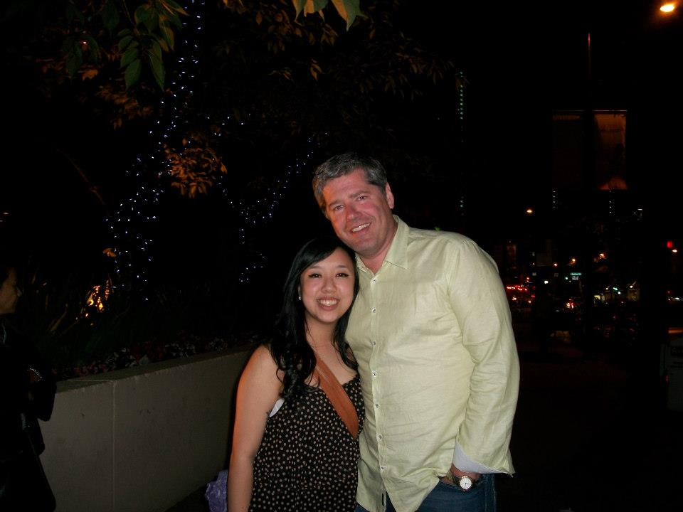 Me and Uncle Richard posing for a picture in summer 2012. He's wearing a light green button up, and I'm wearing a black tank top with a small brown polka dot pattern. We're both smiling and a little hazy-eyed from drinking at a family get-together in downtown Vancouver.