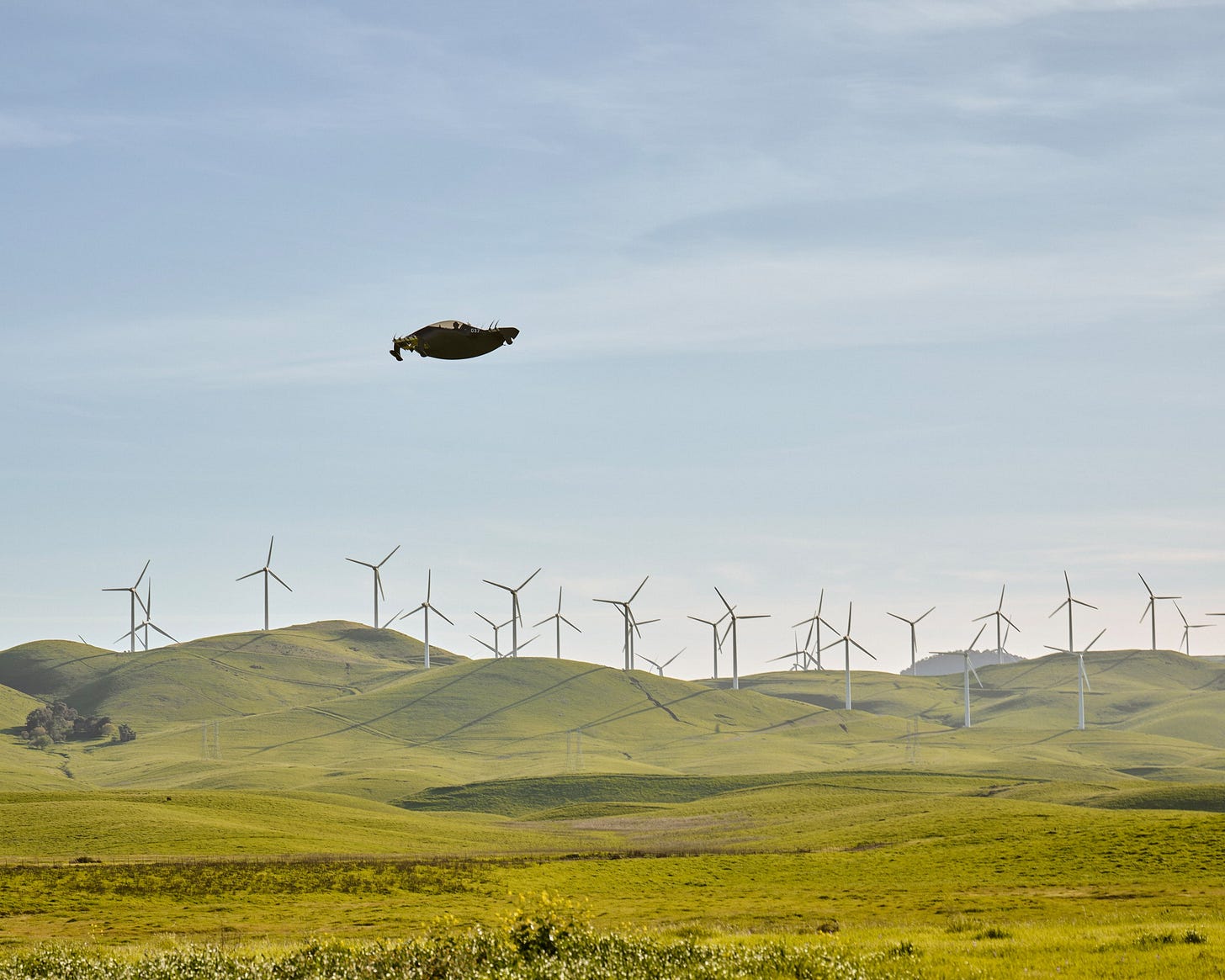 A flying car flies over a landscape of windmills and hills. A flying car flies over a landscape of windmills and hills.
