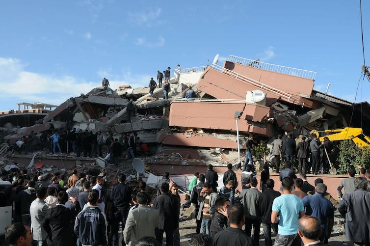 A building destroyed by the earthquake with people standing in front of it. A building destroyed by the earthquake with people standing in front of it.