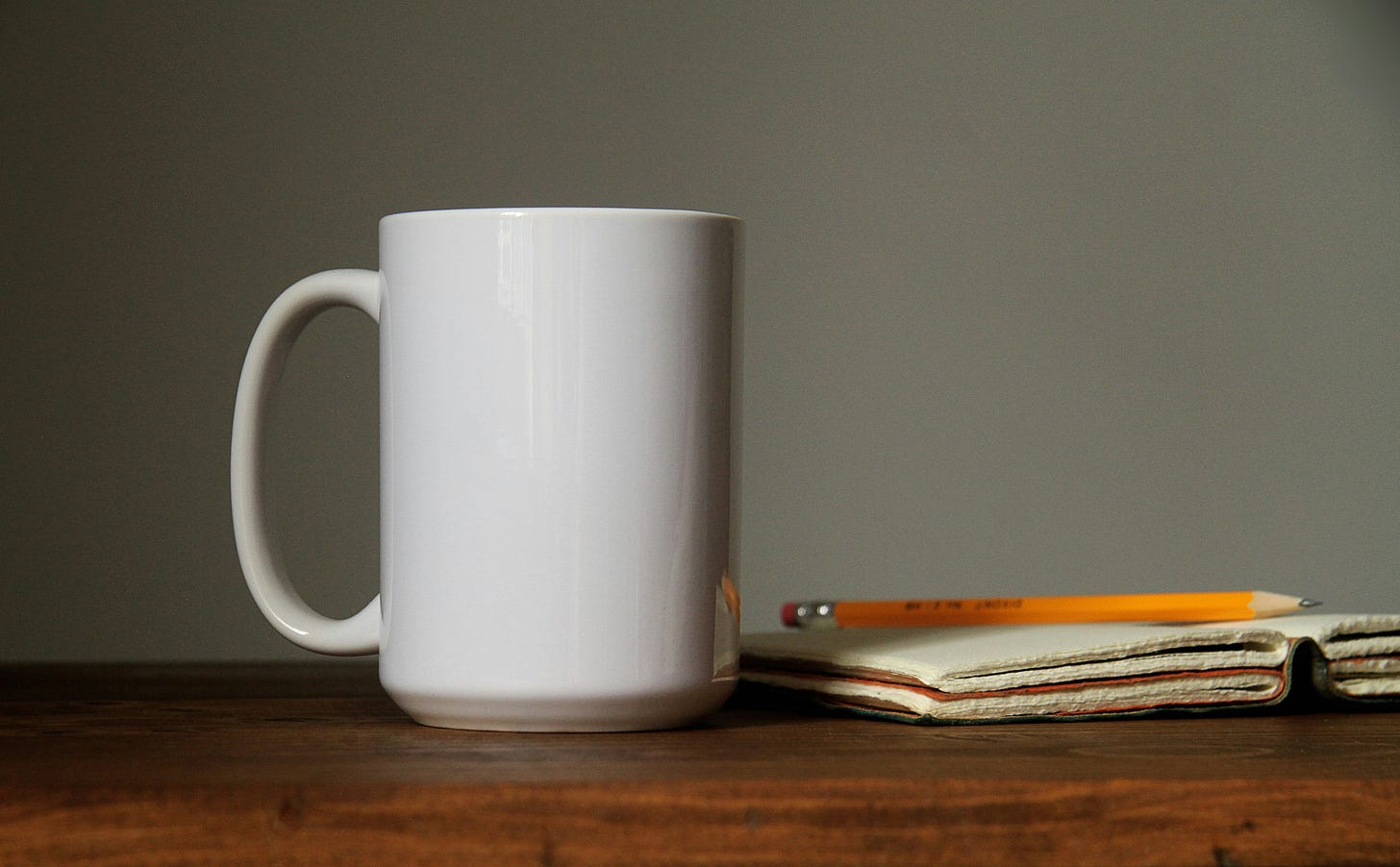 Image of white coffee mug with a journal and a #2 pencil.