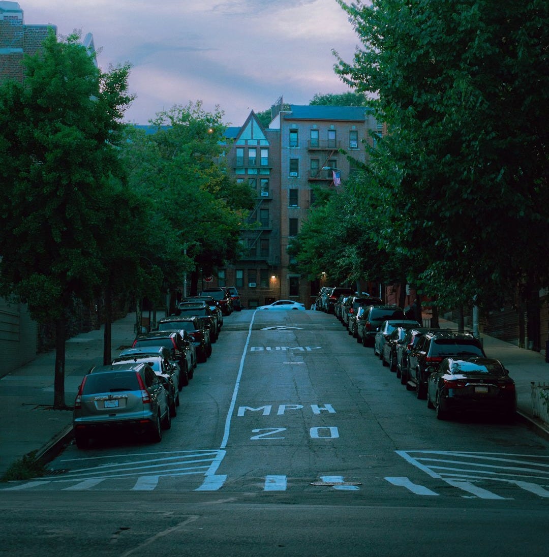A street lined with parked cars next to tall buildings
