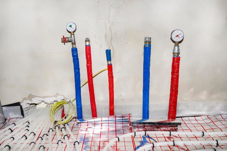 Pipes with hot and cold water coming out of the floor and pressure gauges mounted at the ends