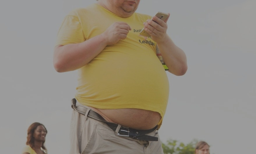 man in yellow shirt and brown pants using smartphone