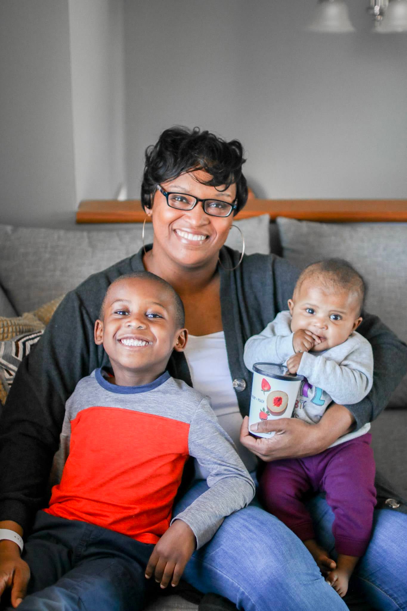 Nicole Washington sitting on the couch with her kids on her lap