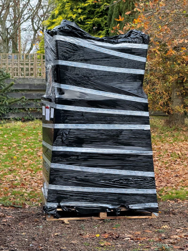 A large pallet with black polythene covering a big rectangular object.
