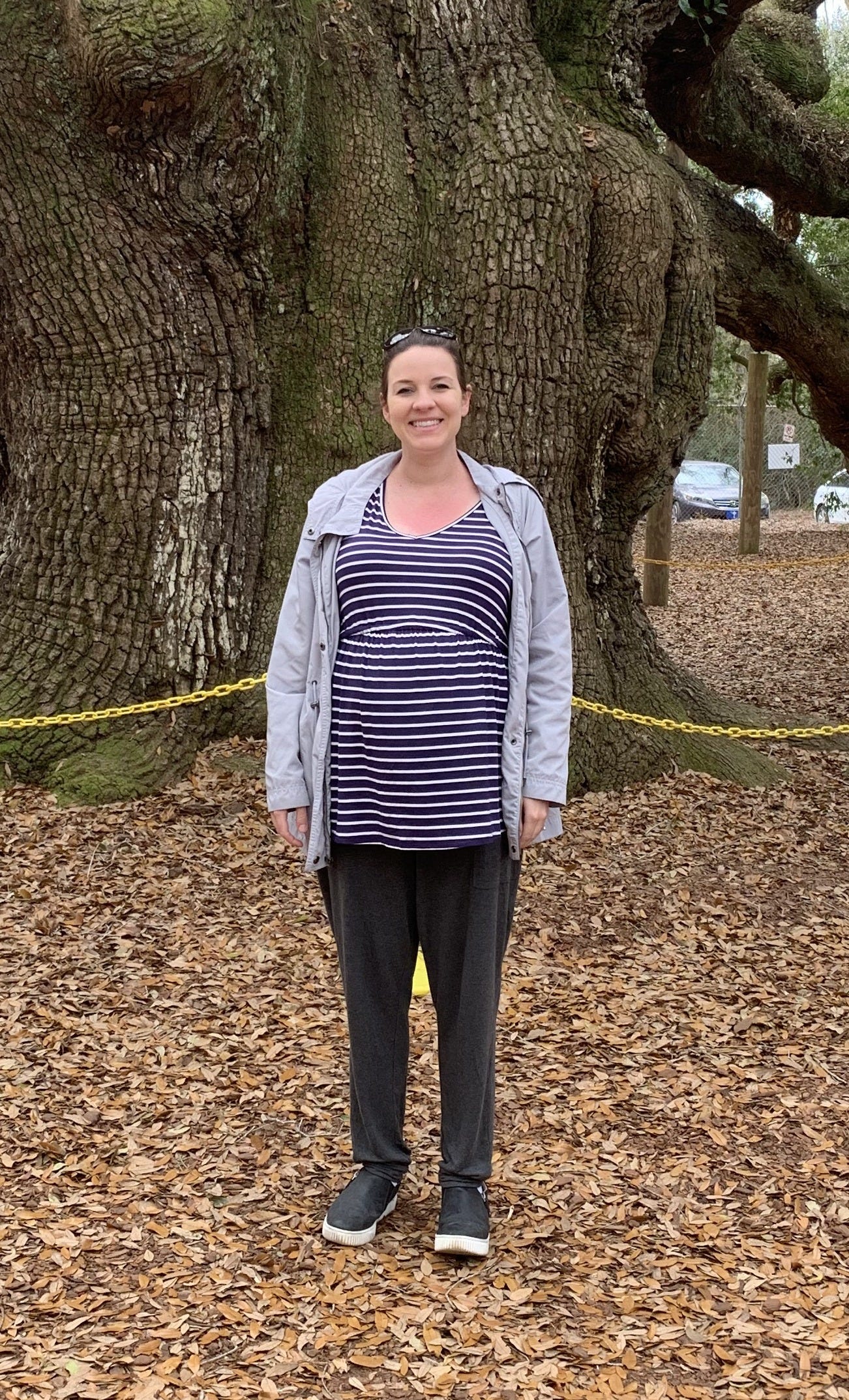A pregnant mom stands before a large tree. A pregnant mom stands before a large tree.