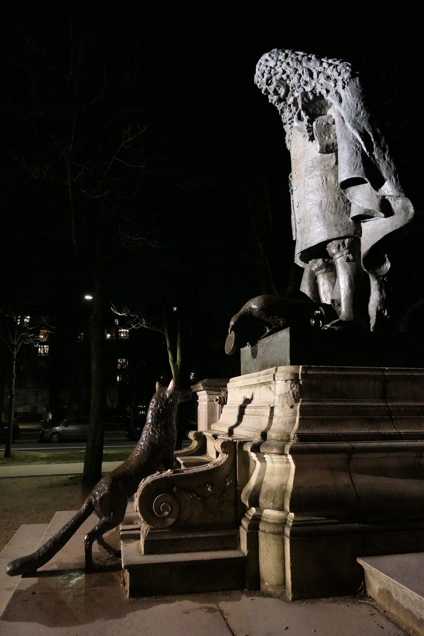 A nighttime photograph of a bronze statue in Paris, featuring a historical figure with long, curly hair and an elaborate coat, gazing down at a fox climbing the pedestal. The scene is illuminated dramatically against a dark background, with soft lighting highlighting the details of the statues and surrounding architecture. A nighttime photograph of a bronze statue in Paris, featuring a historical figure with long, curly hair and an elaborate coat, gazing down at a fox climbing the pedestal. The scene is illuminated dramatically against a dark background, with soft lighting highlighting the details of the statues and surrounding architecture.