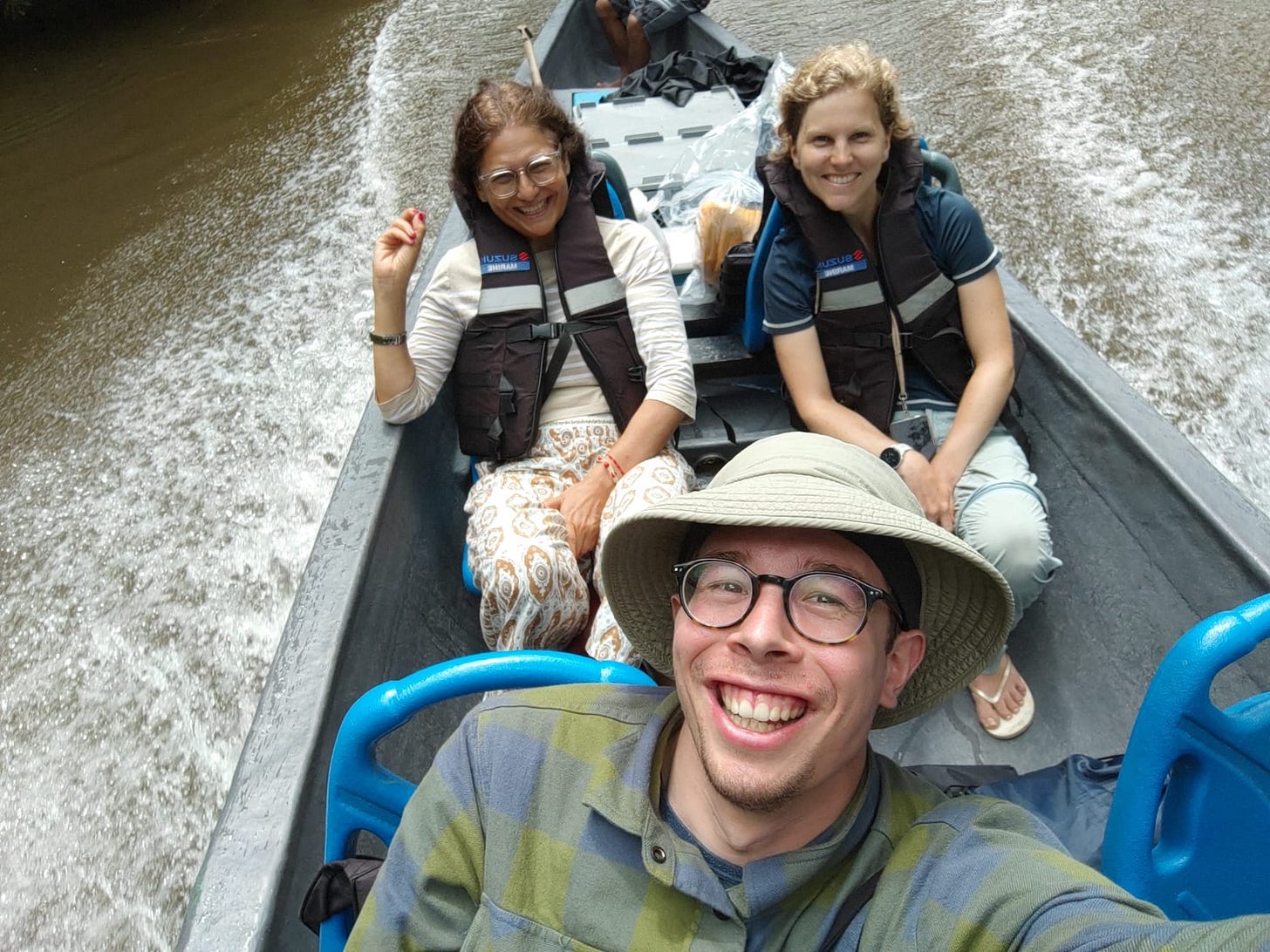 Dos mujeres y un hombre joven en barca a motor tipo piragua en Cuyabeno, Ecuador.