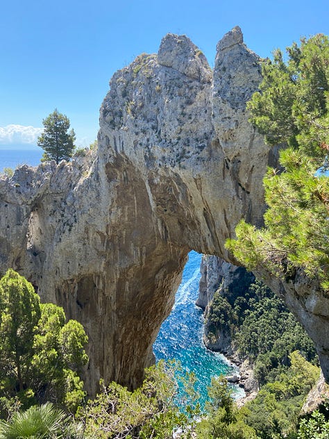 A gallery of three images of rock formations providing different views down to the Mediterranean Sea that surrounds the island of Capri. The rock formations provide different frames looking down from a high point on the island to the water below and the trees that line the images, peeking their green in. The sun shines from different angles in the different pictures.