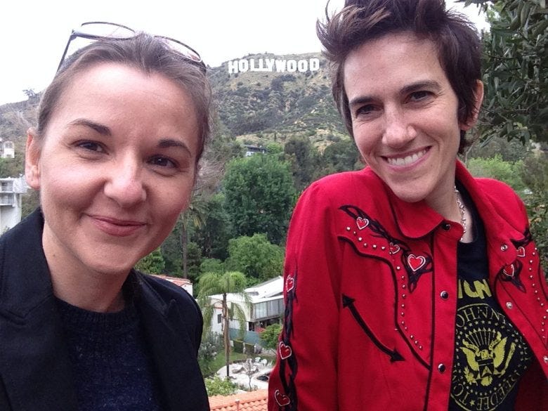 two women take a selfie with the iconic Hollywood sign in the background