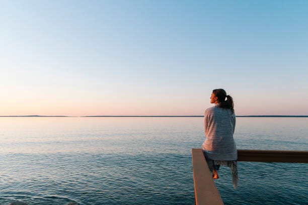 young woman sitting on edge looks out at view - people chilling stock pictures, royalty-free photos & images