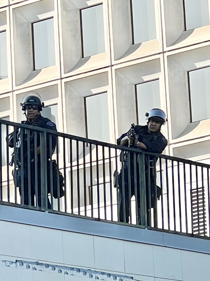 First photo shows cops behind a chained fence while a black cloud of smoke is behind them. The second photo shows two police officers holding what to appear to be live ammon weapons.
