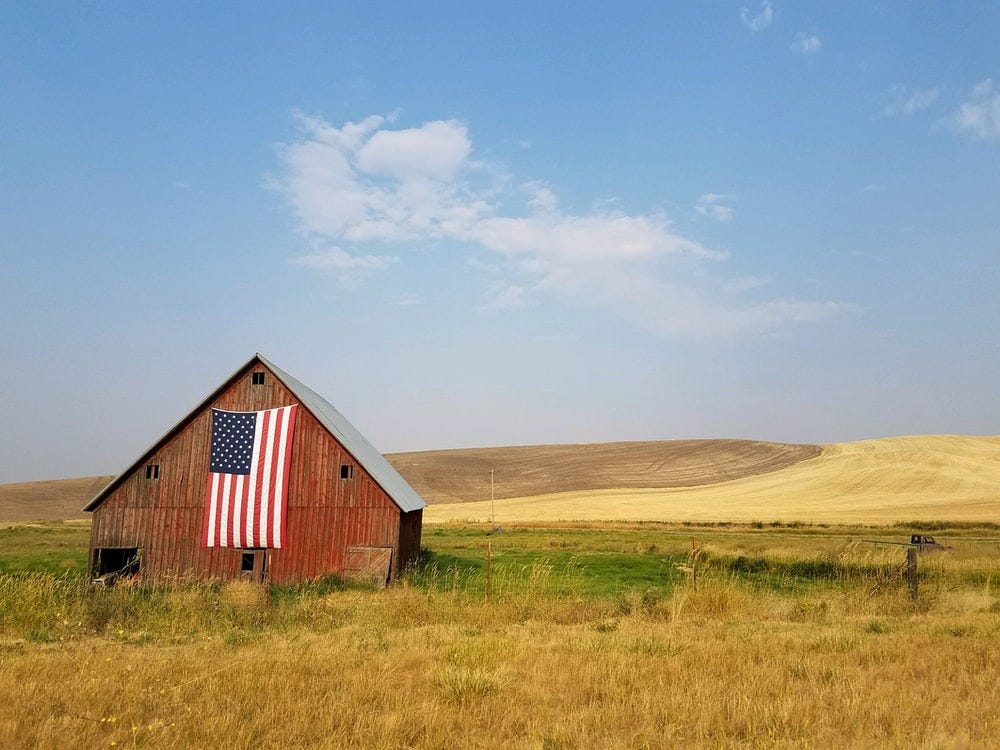 flag of United States of America hanged on brown house during daytime flag of United States of America hanged on brown house during daytime