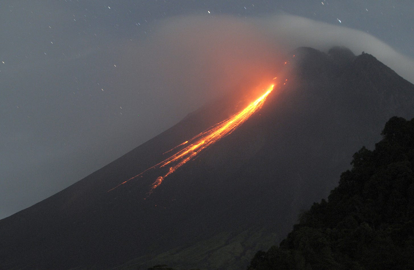 Mount Merapi, which emits chunks of lava when it erupts several times, is seen from Turgo village, Sleman district in Yogyakarta, Indonesia in the early morning, on May 22, 2022. The Indonesian Center for Research and Development of Geological Disaster Technology (BPPTKG) noted that the activity of Mount Merapi was clearly visible and the smoke from the crater under low pressure was observed to be white with moderate to thick intensity, and 20-50 m high above the crater peak. In addition to hot clouds of avalanches, incandescent lava avalanches were also observed 10 times the maximum sliding distance of 2,000 meters to the southwest. (Photo by Dasril Roszandi/Anadolu Agency via Getty Images)