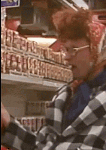 a man wearing glasses and a plaid shirt is standing in front of a store shelf
