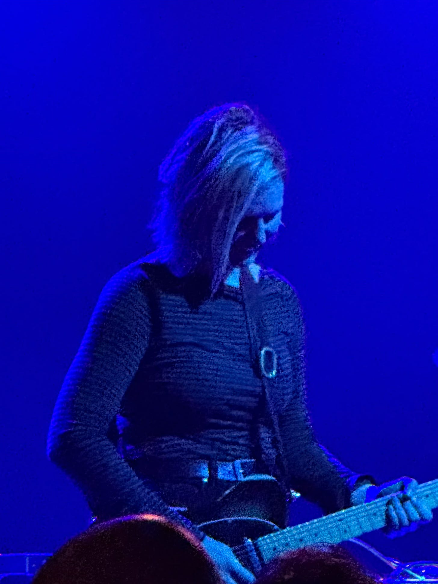 Rachael Wood playing guitar under blue stage lights