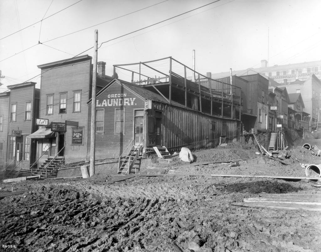 A corner in Seattle's Japantown circa 1905. There are several wooden buildings set back from a "street" of open mud with wooden planks laid down. A corner in Seattle's Japantown circa 1905. There are several wooden buildings set back from a "street" of open mud with wooden planks laid down.