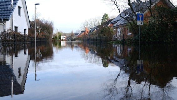 Eine Straße in einem Wohngebiet in Lilienthal (Landkreis Osterholz Landkreis Osterholz) steht unter Wasser. © dpa-Bildfunk Foto: Markus Hibbeler/dpa
