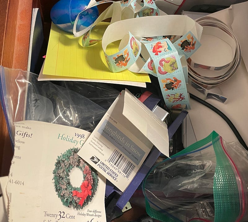 A cluttered drawer with postage stamps in it.