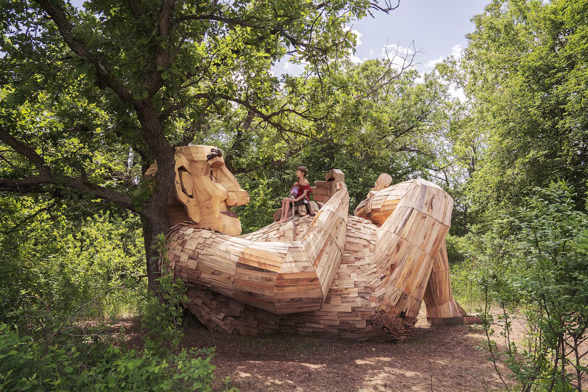 A person sitting on a wooden sculpture

Description automatically generated