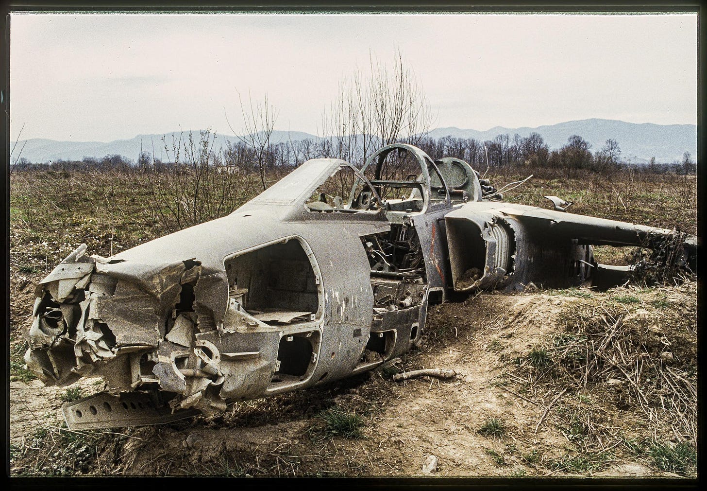 An evocative image of an abandoned military aircraft in a Bosnian field, 1997, a silent testament to past conflicts.