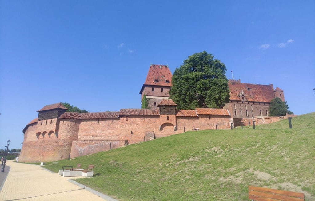 Malbork Castle, seen from the riverside, on the South side. Behind the high outer walls, the High Castle stands several storeys higher. All made of brick, it's a perfect storybook castle.