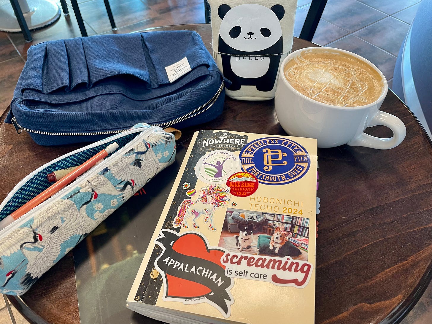a photo of a planner, two pen cases, and a canvas bag sitting on a cafe table