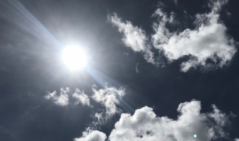 The sun is shining through the clouds in the sky