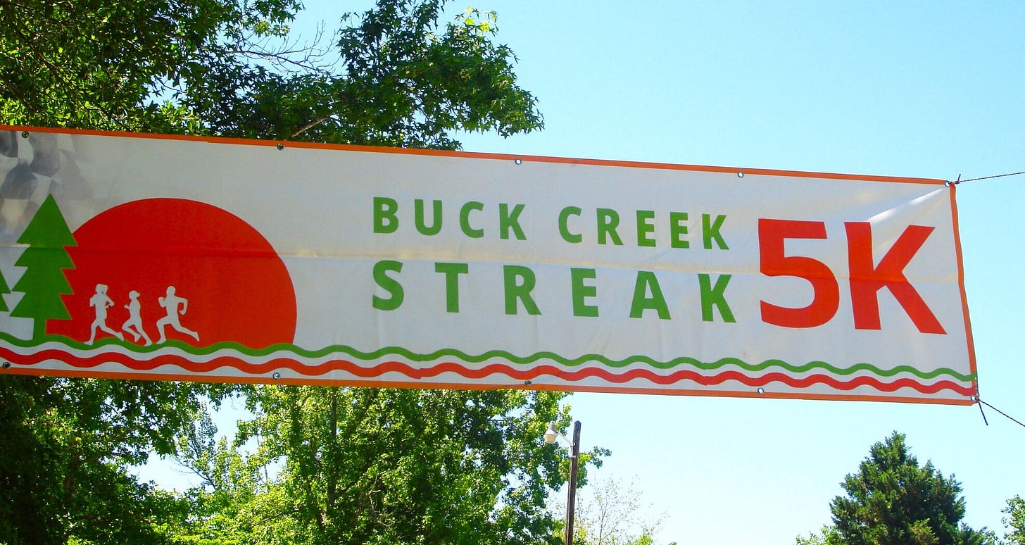 A large banner hangs high reading "Buck Creek Streak 5K"