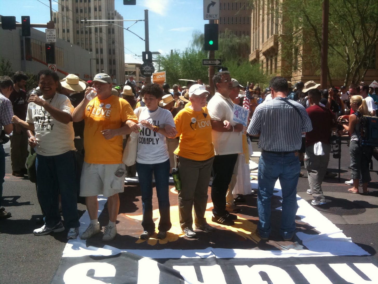 A group of people standing in a circle in the middle of an intersection with arms locked together