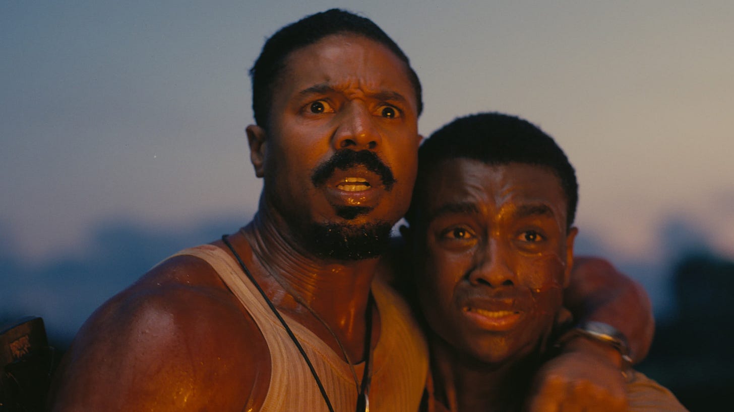 Sinners | Still features Michael B. Jordan and Miles Caton facing an illuminated entity.