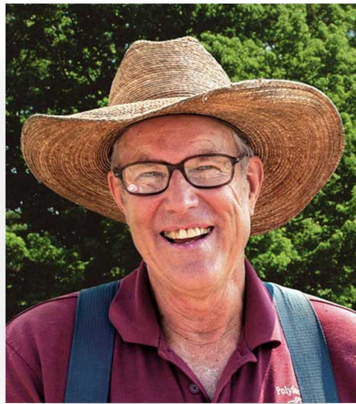 Joel Salatin in a wide straw hat and maroon shirt smiling outdoors in front of green trees. Joel Salatin in a wide straw hat and maroon shirt smiling outdoors in front of green trees.