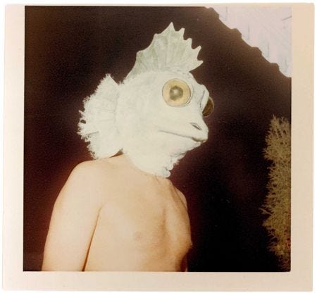 This may contain: an odd looking creature with hair on it's head and eyes, standing in front of a dark background