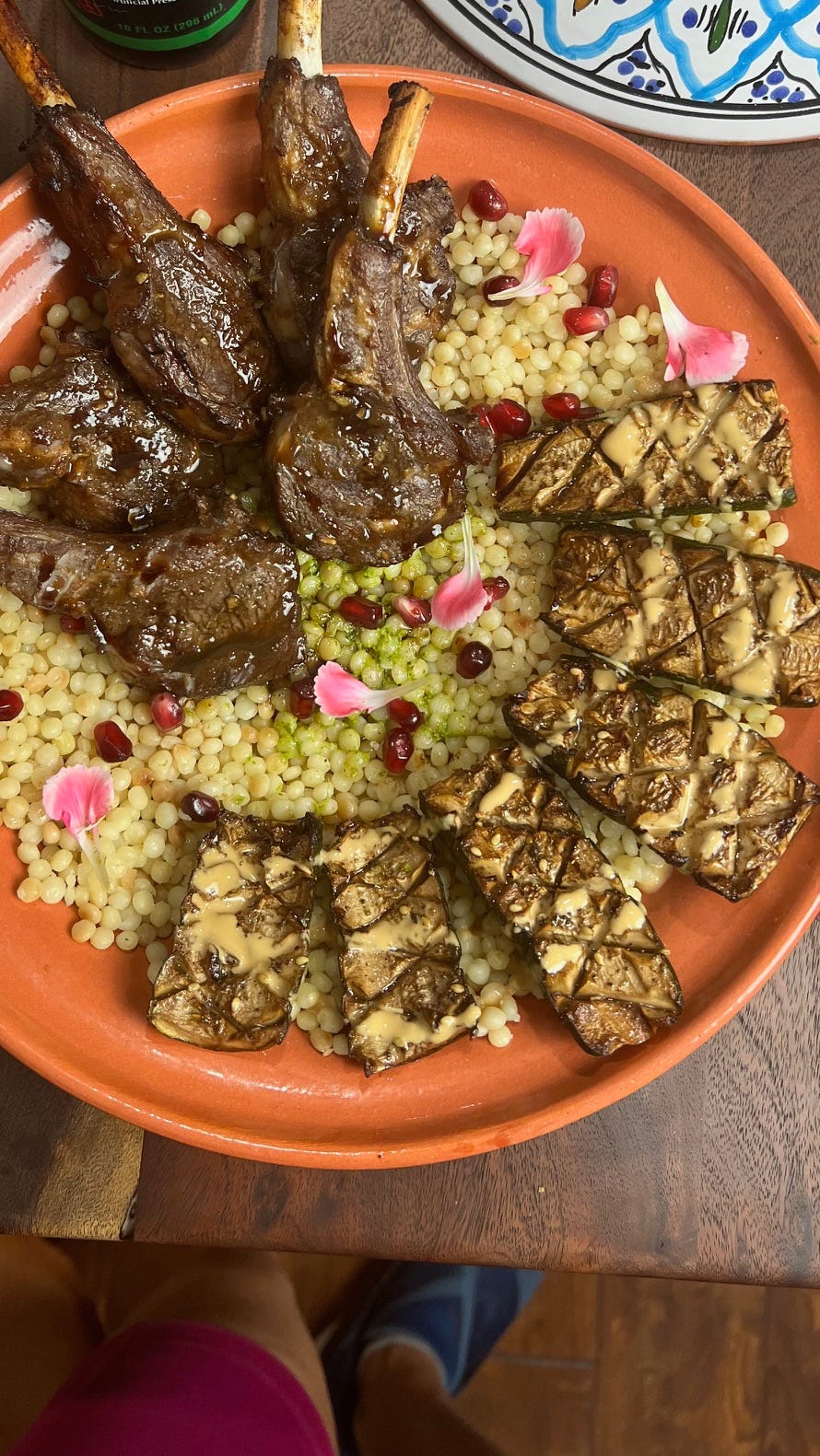 Chef Mareya’s lamb chop with grilled eggplant and tahini za’atar drizzle on an orange plate