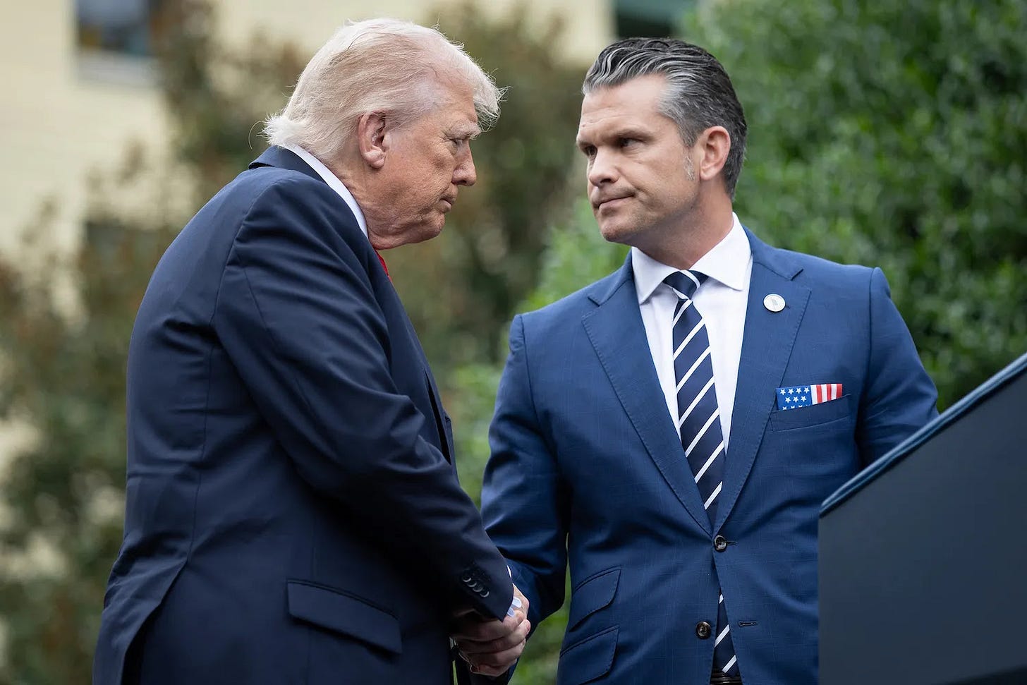 U.S. President Donald Trump shakes hands with U.S. Defense Secretary Pete Hegseth.