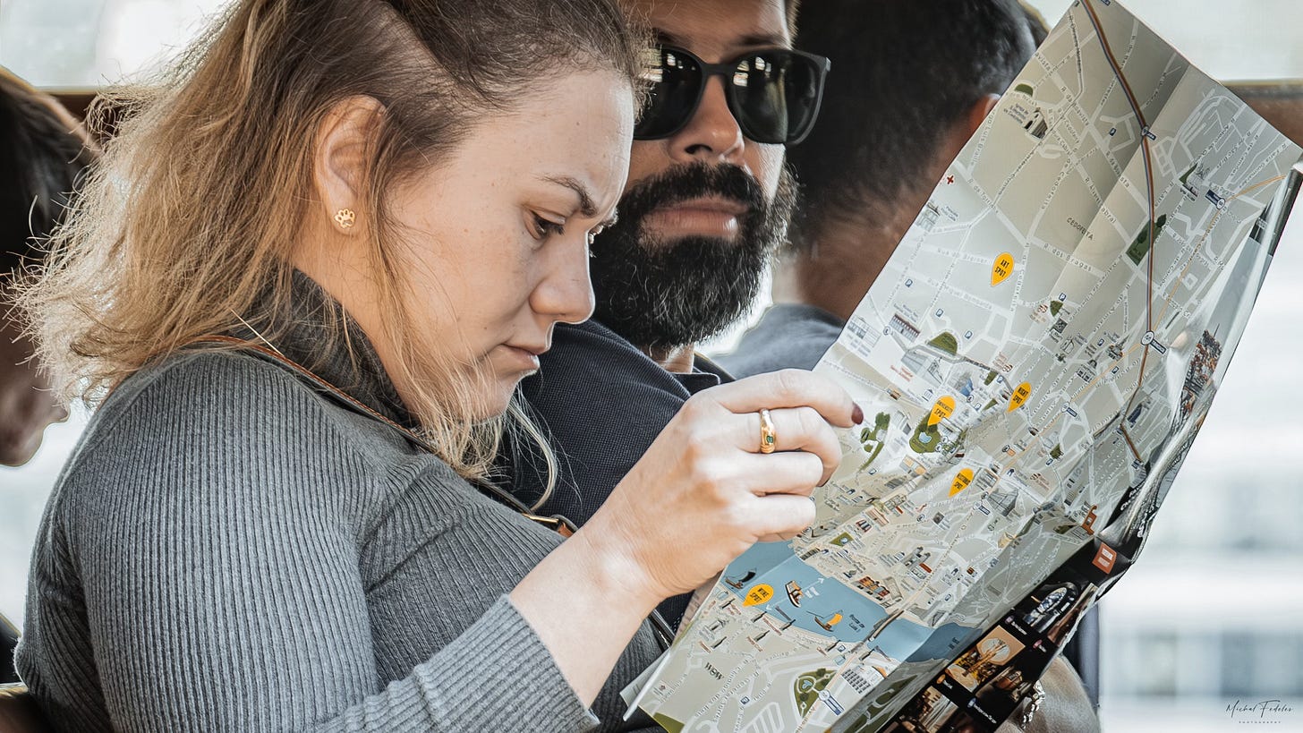 A woman examining a map with a man sitting beside her A woman examining a map with a man sitting beside her