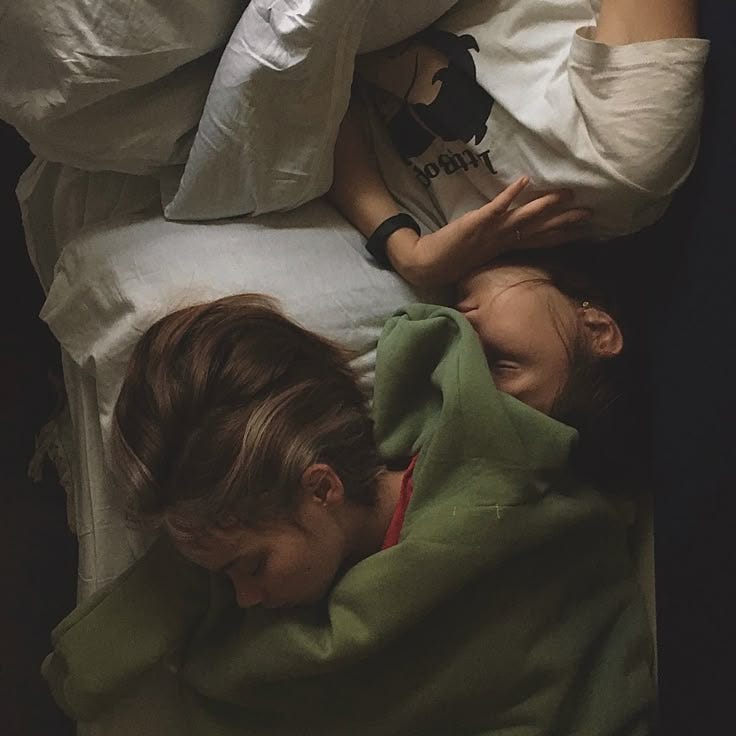 This may contain: a woman laying in bed next to a child