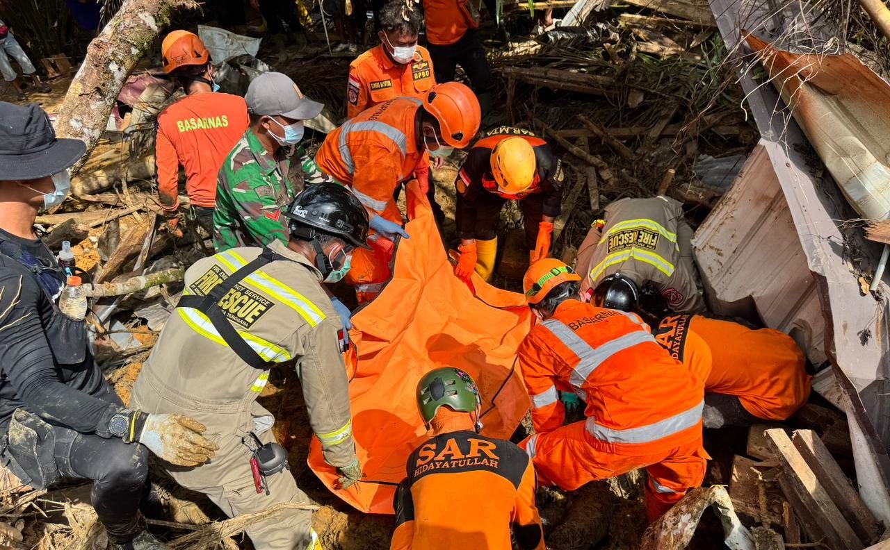 Several people in orange uniforms from the National Search and Rescue Agency are lifting a body found in a muddy area due to flooding in late November 2025 in North Sumatra. Several people in orange uniforms from the National Search and Rescue Agency are lifting a body found in a muddy area due to flooding in late November 2025 in North Sumatra.