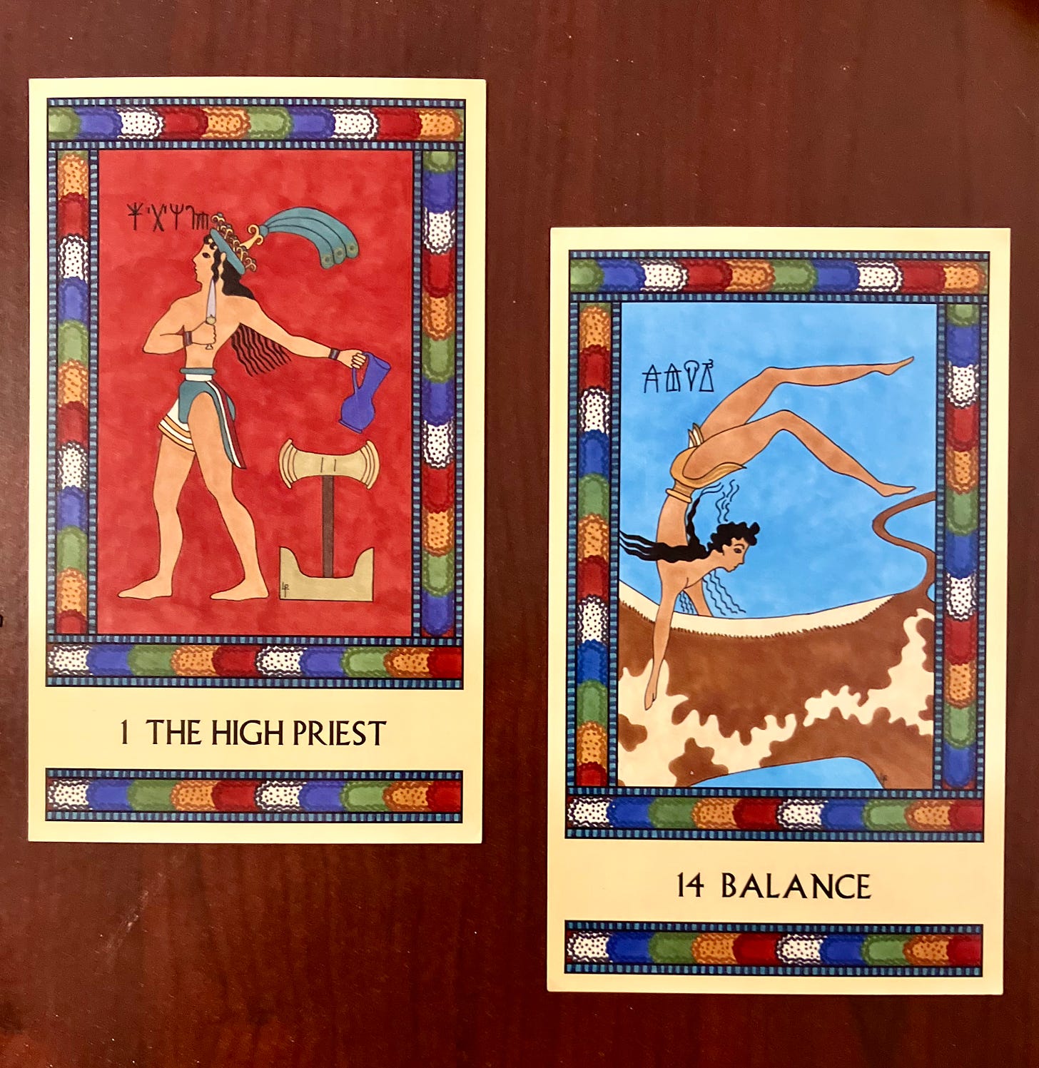 Two Minoan Tarot cards on a dark wood background. They both have multicolored borders. The High Priest shows a Minoan man wearing a loincloth and codpiece, facing left, surrounded by the symbols of the four suits. Balance shows a loincloth-clad bull leaper balancing upside down on the back of a brown and white spotted bull.