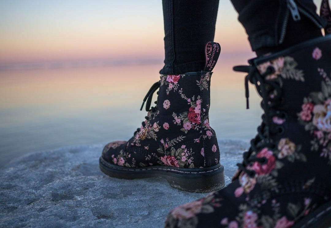 person wearing black and pink floral boots