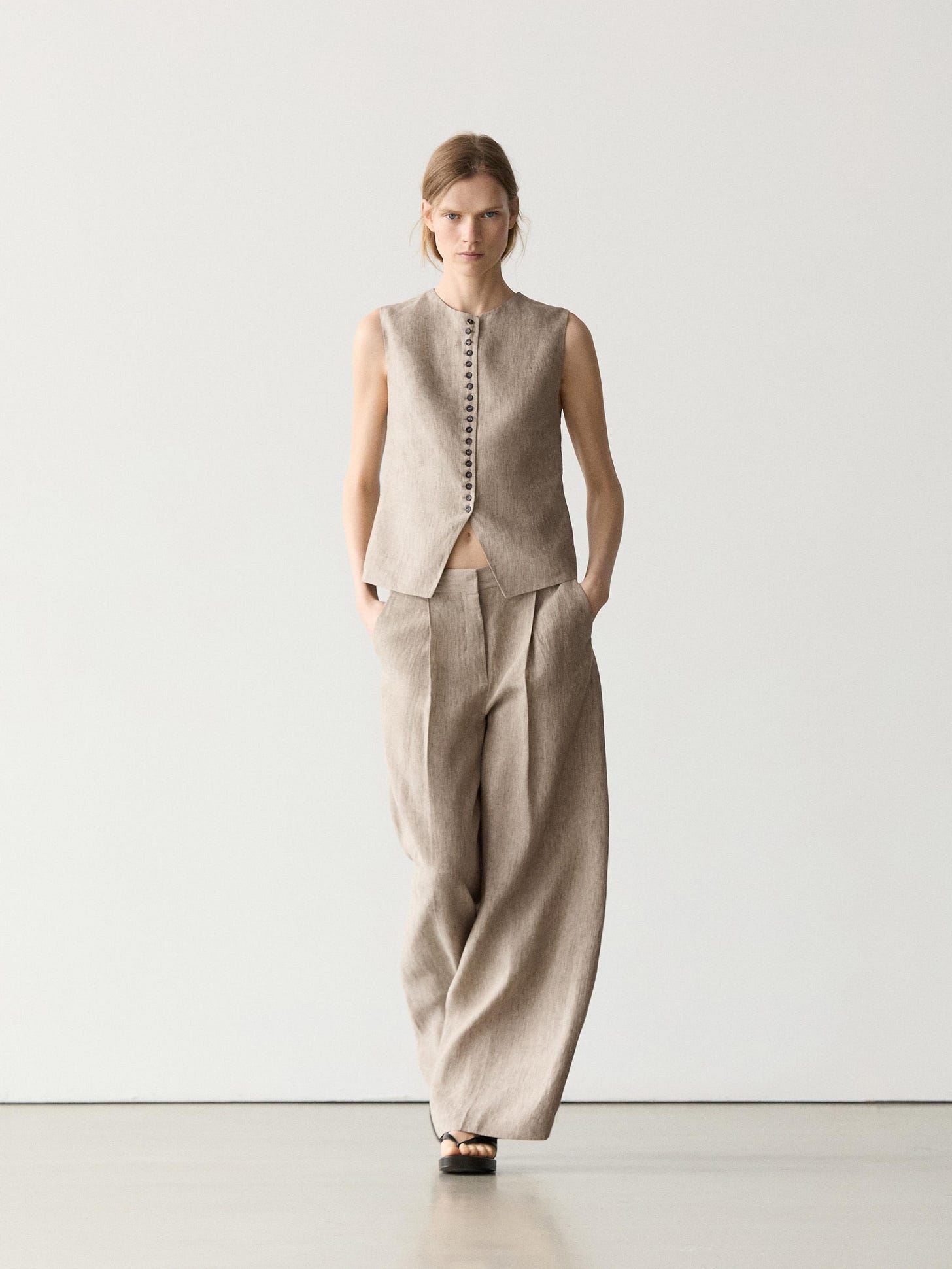 Beige sleeveless vest and matching wide-leg pants set with front button closure and side pockets.